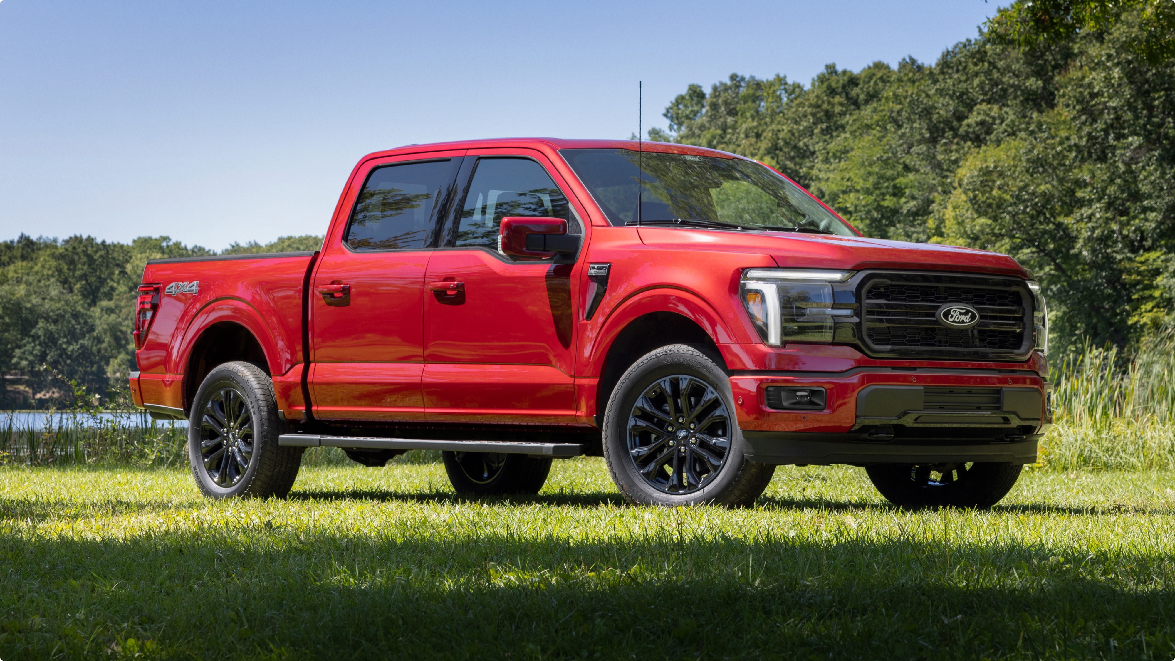 Ford F-150® roja estacionada sobre el césped con árboles de fondo