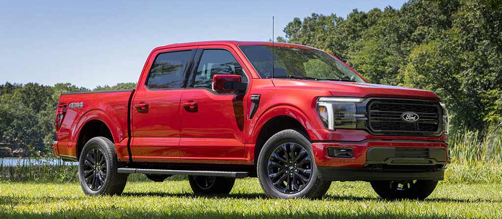 Ford F-150® roja estacionada sobre el césped con árboles de fondo