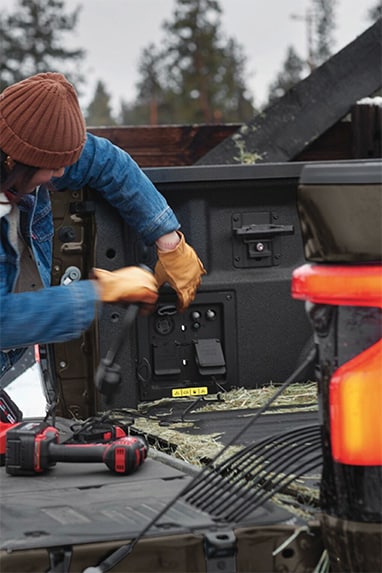 Mujer utilizando los generadores de energia de la caja de una Ford F-150