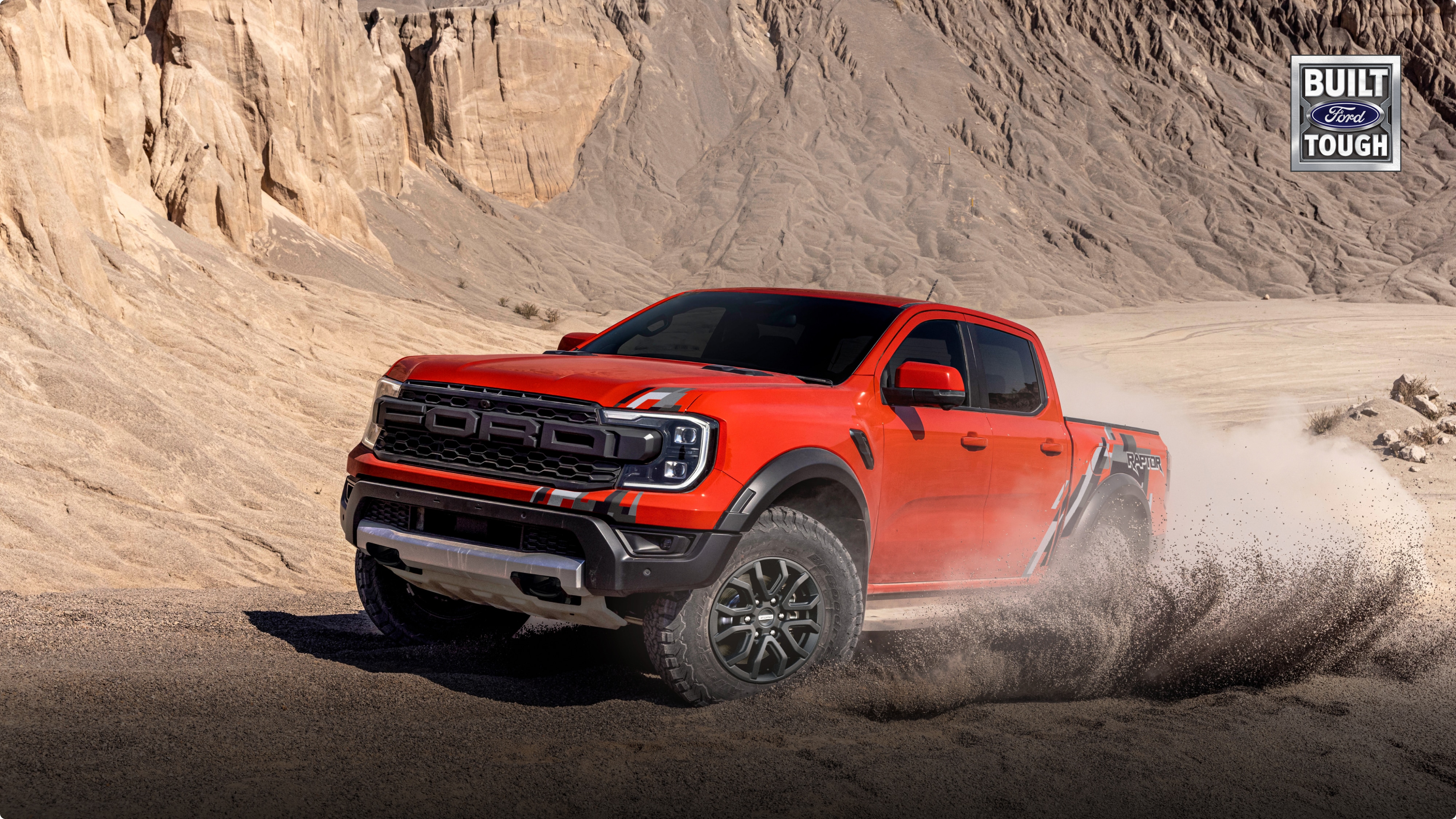 Ford Ranger Raptor naranja en plena acción sobre terreno arenoso y polvoriento