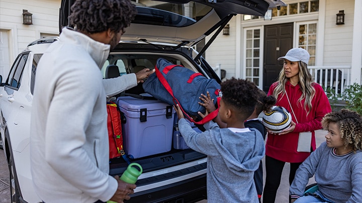 Familia acomodando su equipaje en el baúl de su Ford Explorer